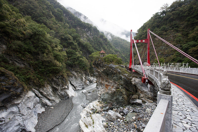 悬索桥横跨树木覆盖，雾气弥漫的山谷，台湾