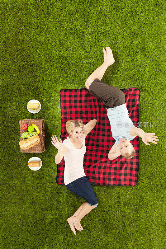 幸福的年轻夫妇躺在野餐和挥手