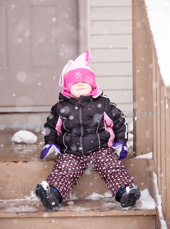 雪中的女孩坐在台阶上