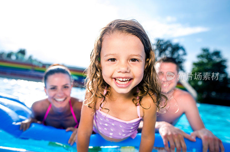 妈妈，爸爸和女儿在游泳池里。阳光明媚的夏天。
