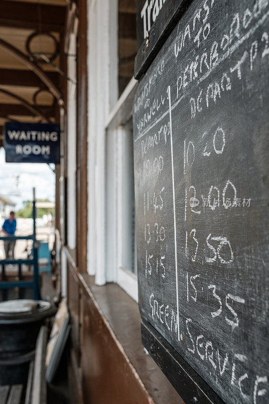 在一个老式火车站的黑板上，手写着旅客列车的时间。