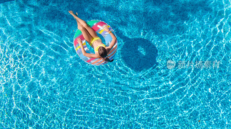 鸟瞰图的女孩在游泳池从上面，孩子游泳在充气圈甜甜圈和有乐趣的水在家庭度假