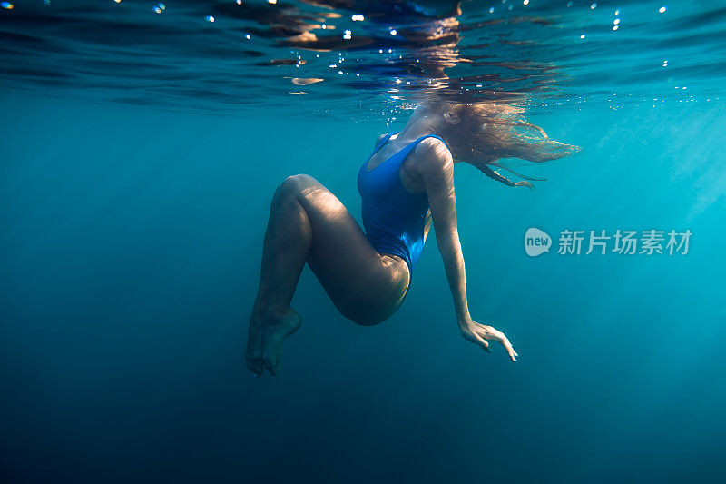水下女子肖像在蓝色的海洋与白天的光。