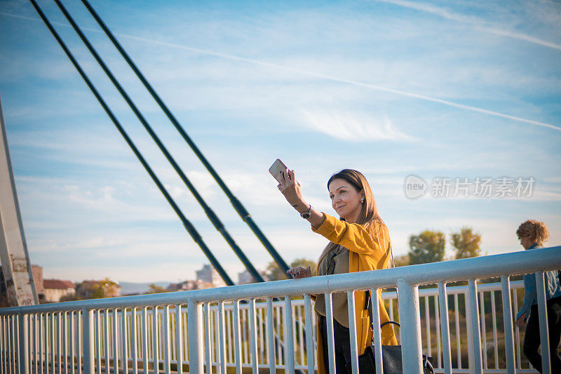 年轻迷人的女商人与她的智能手机交谈和自拍照片