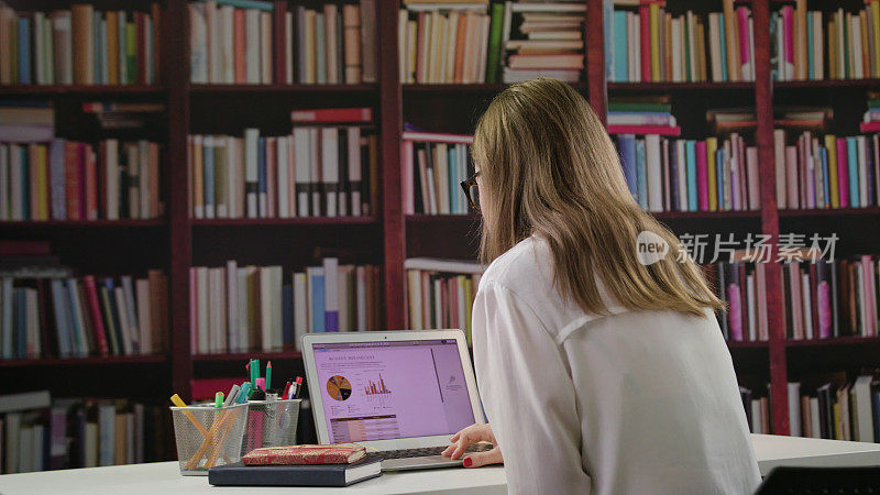 年轻女士在图书馆使用笔记本电脑