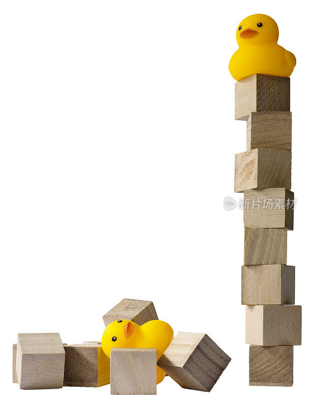 两只橡皮鸭，一只在木块搭成的高塔上，另一只在一堆倒下的木块上。