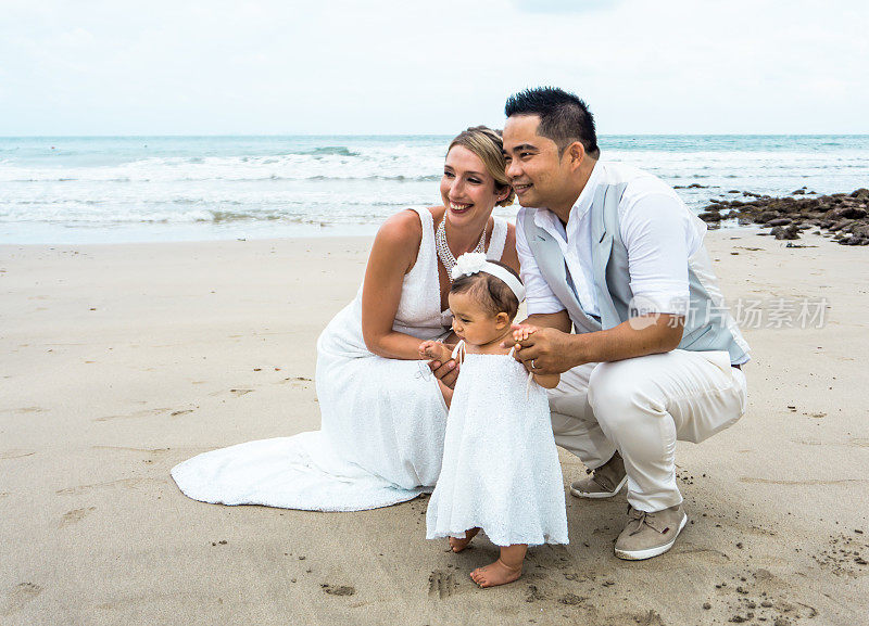 新郎和新娘和小女儿在海滩上