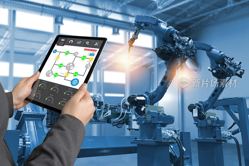 工程师手用平板、重型自动化机械手在智能工厂工业用平板实时过程控制监控系统中的应用。工业第四物联网概念。