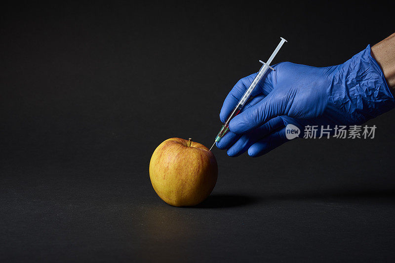 手将手术注射器放入苹果