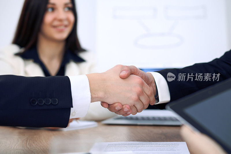 商务人士在会议或在办公室谈判握手的特写。合作伙伴因签订合同而满意