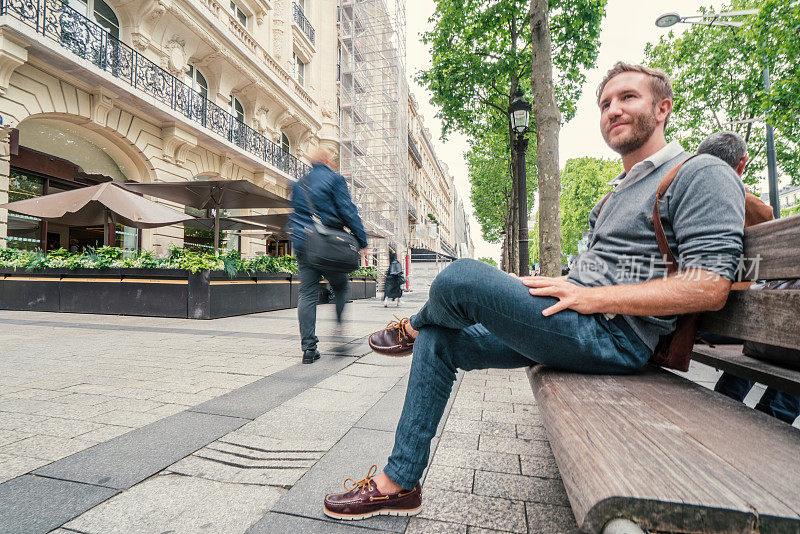 年轻人坐在巴黎街头的长椅上，法国人的城市放松概念