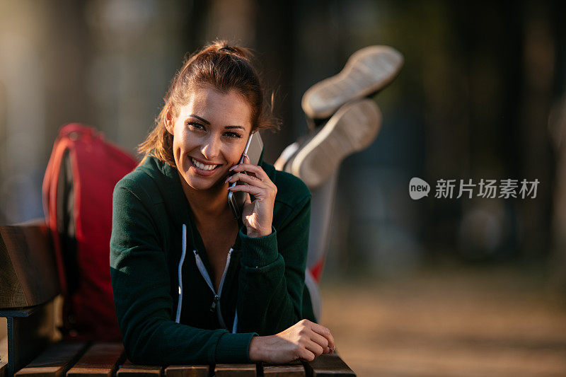 漂亮的年轻运动女性与智能手机在户外