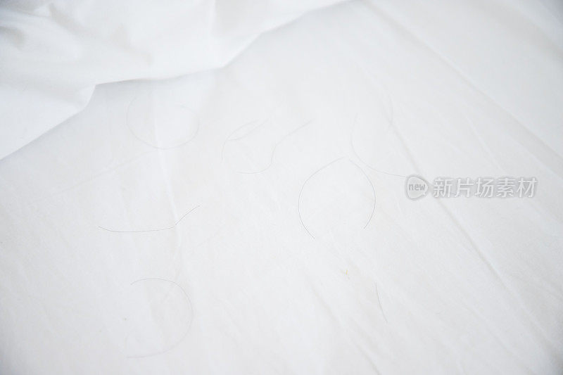 白色床垫上的黑毛靠近白色枕头，概念:头发脱落问题