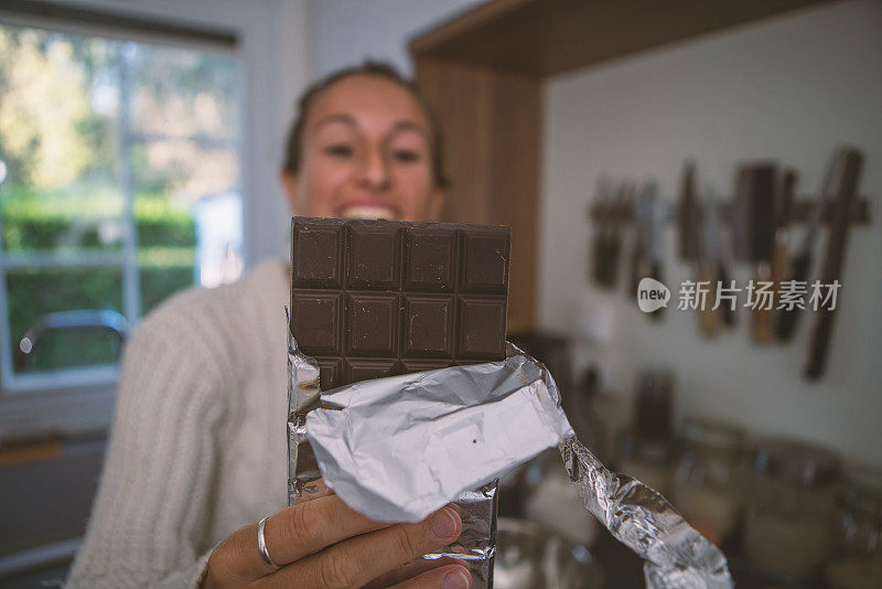 年轻女子在厨房吃巧克力，近距离观看;人们对甜食的嗜好概念