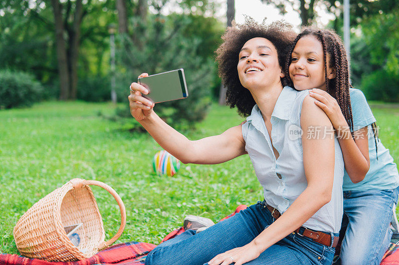 快乐的女人在野餐时与女儿自拍