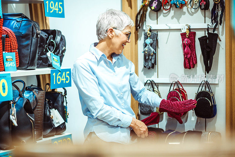 年长的女性在一个包和饰品店试穿一些闪闪发光的天鹅绒手套