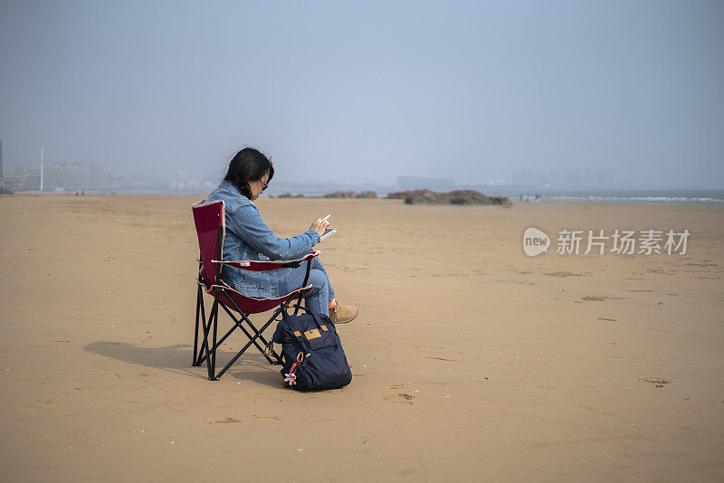 年轻女性在海滩上素描