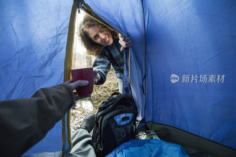 微笑的中年妇女把咖啡杯给一个在帐篷里的男人