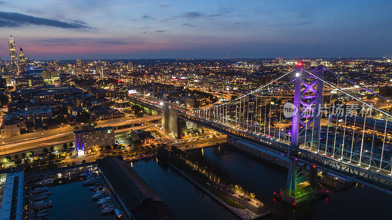 从本杰明富兰克林桥和特拉华河老城的码头上方俯瞰费城市中心的夜景。