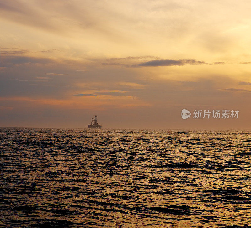 戏剧性的乌云密布的天空掠过深色的水面，海面上泛起涟漪，阳光泛黄。