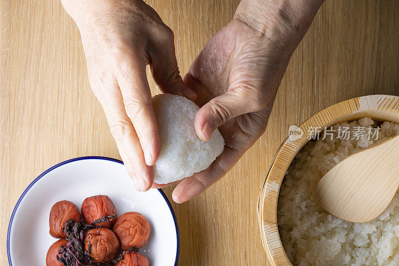 日本年长妇女拿着饭团和米饭煮的梅竹