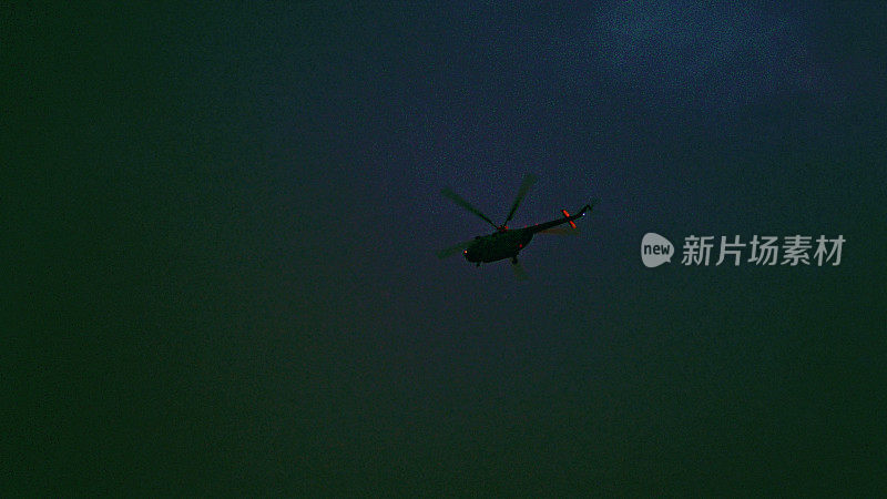 直升机在黑暗的天空中飞行。保安摄像机视图