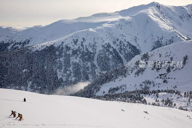 在冬季高山滑雪度假区，单板滑雪爱好者在刚下过的粉状雪中享受乐趣