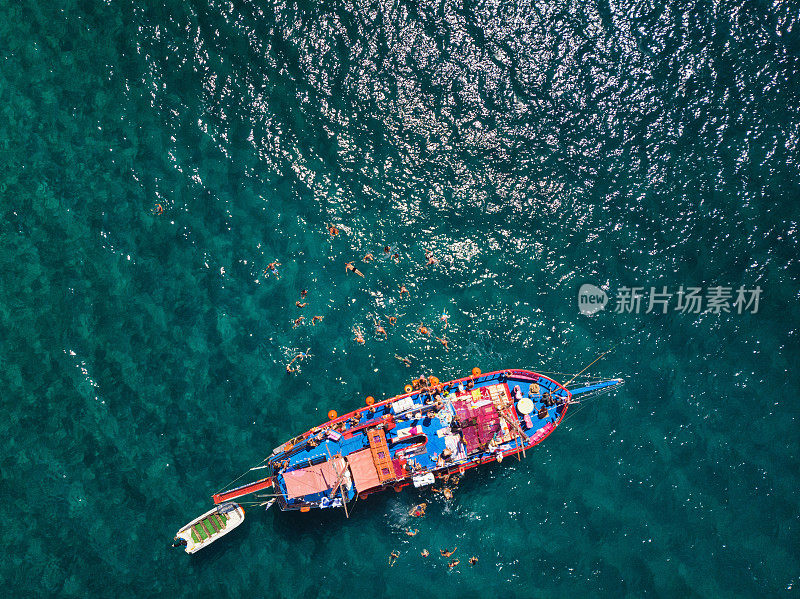 在炎热的夏天，红色游轮的鸟瞰图。俯视图的人正在船周围游泳