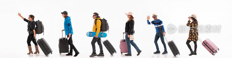 一群不同种族、不同年龄的旅行者带着他们的行李箱走着
