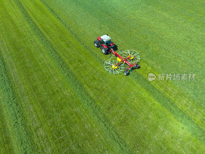 拖拉机拉着旋转耙从草地上收集干草
