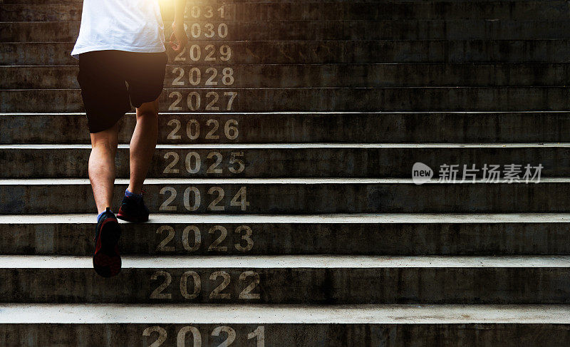 一名男子跑上户外楼梯，上面写着2022、2023、2024到2031年的新年数字