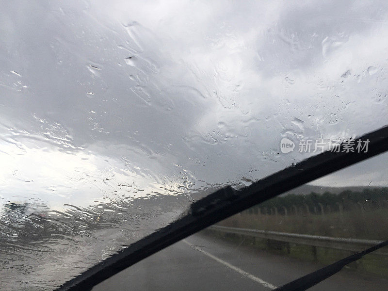 下雨天开车。雨刷带雨水和路面