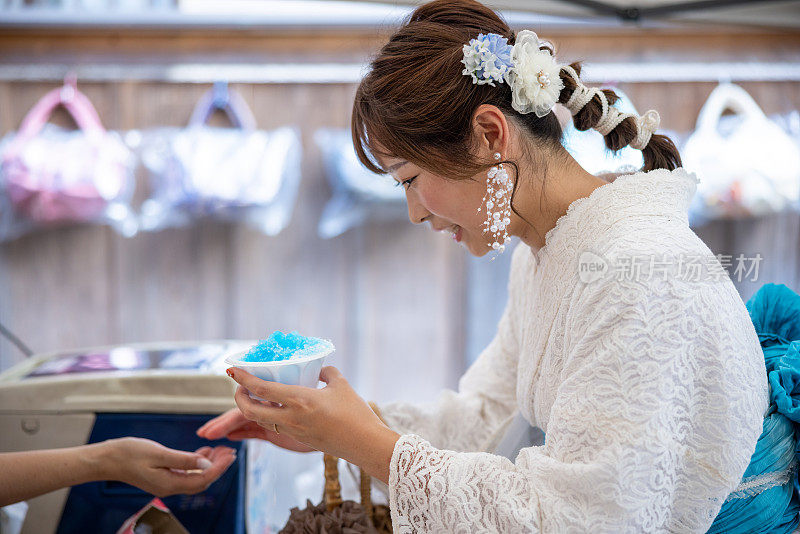 穿着白色蕾丝和服的女人在买“kakigori”刨冰