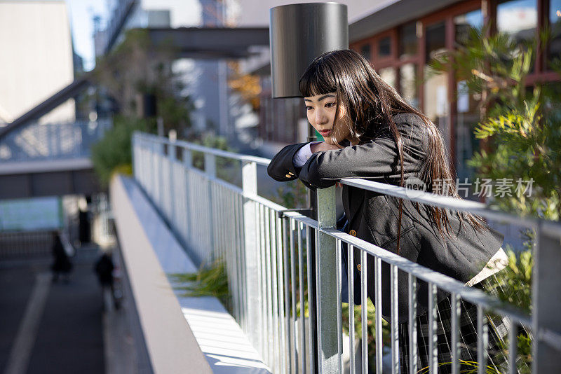 城市里的高中女孩倚在扶手上