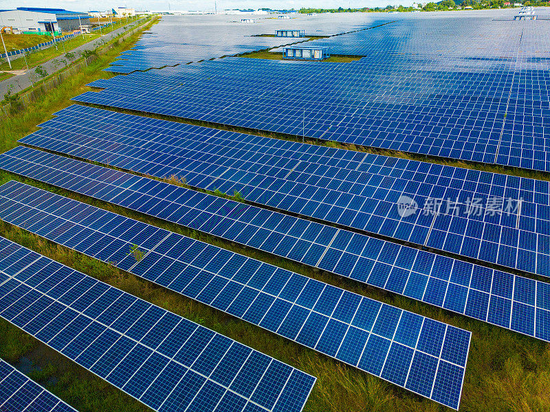 太阳能农场的太阳能电池板(太阳能电池)的俯视图，绿树和阳光反射。农村的光伏工厂田地，蓝天。