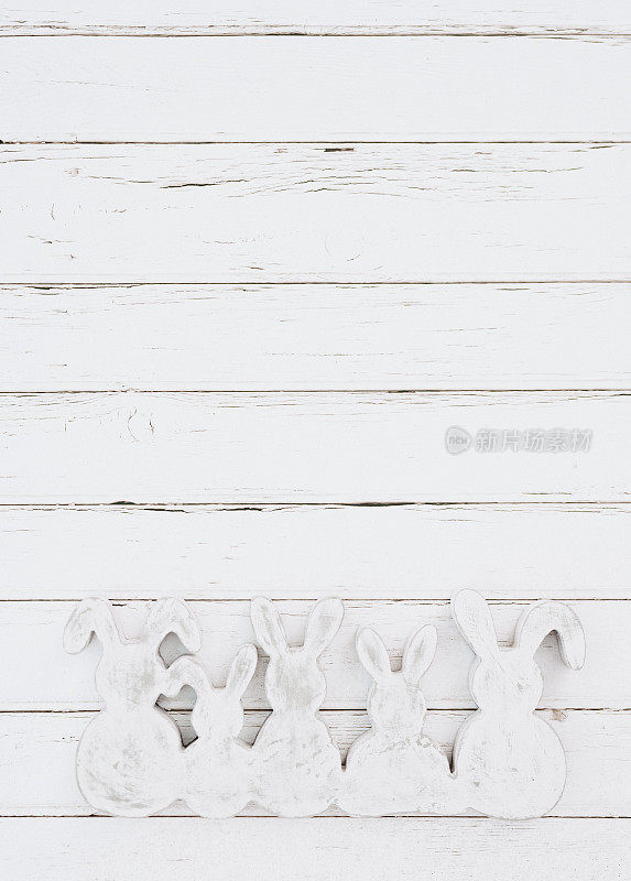 简单的一种颜色的平铺白色和灰色的木制复活节兔子形状的白色木制背景与慷慨的复制空间