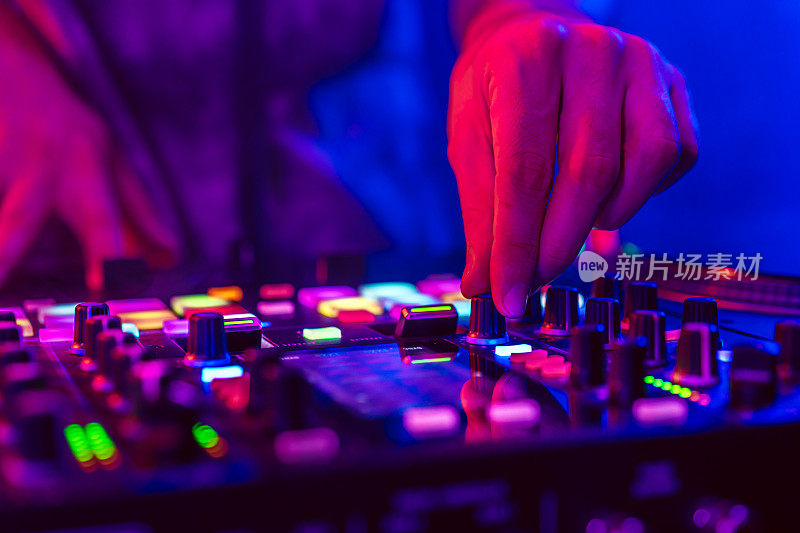近距离的DJ手在DJ控制台混音在音乐会期间在俱乐部