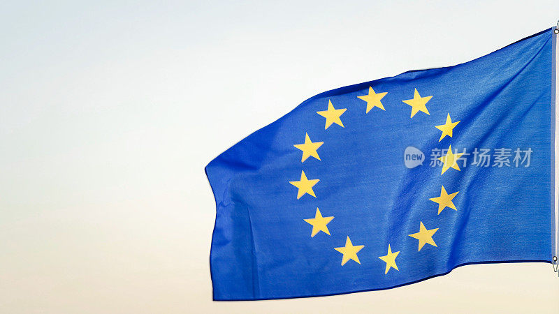 欧洲联盟旗或欧洲旗帜，蓝色背景上有十二颗金色的星星，代表欧洲人民的联盟。天空背景上的旗杆上飘扬的欧盟旗帜