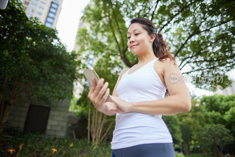 中年女性健身者在户外用手机测量心跳