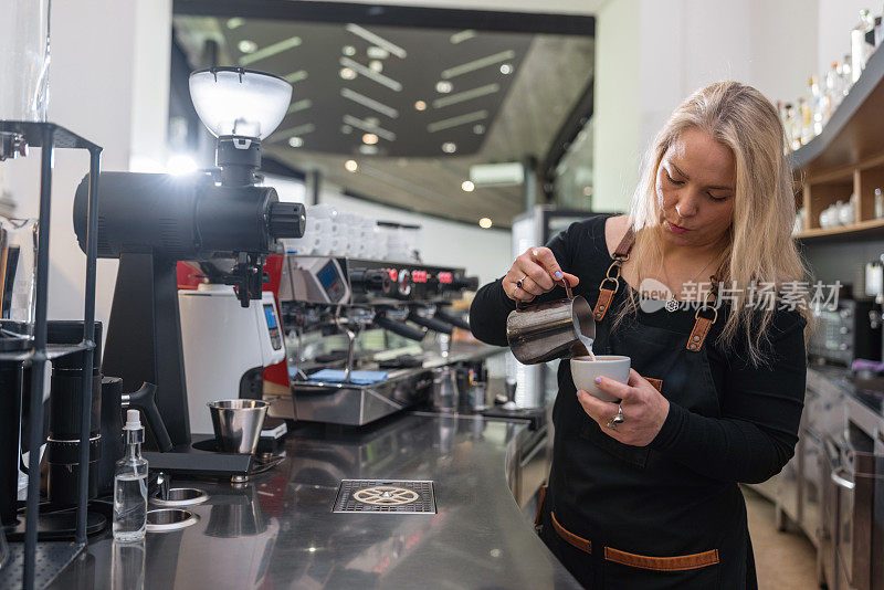 专注的成年白人女咖啡师在一家专业咖啡店做咖啡
