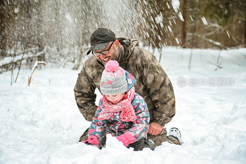 爸爸和女儿走在冬天的森林里