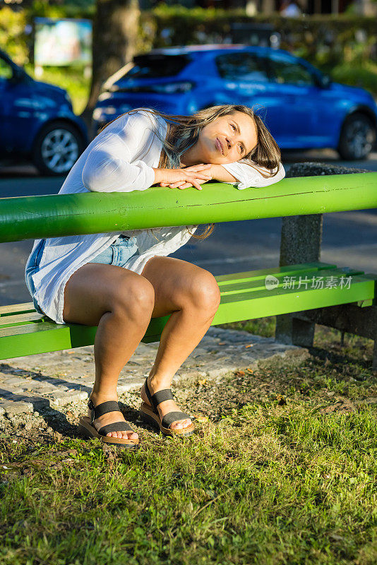 一个女人坐在河边的长凳上放松。