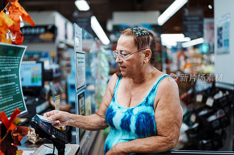 一位老年妇女在超市收银台用信用卡结账