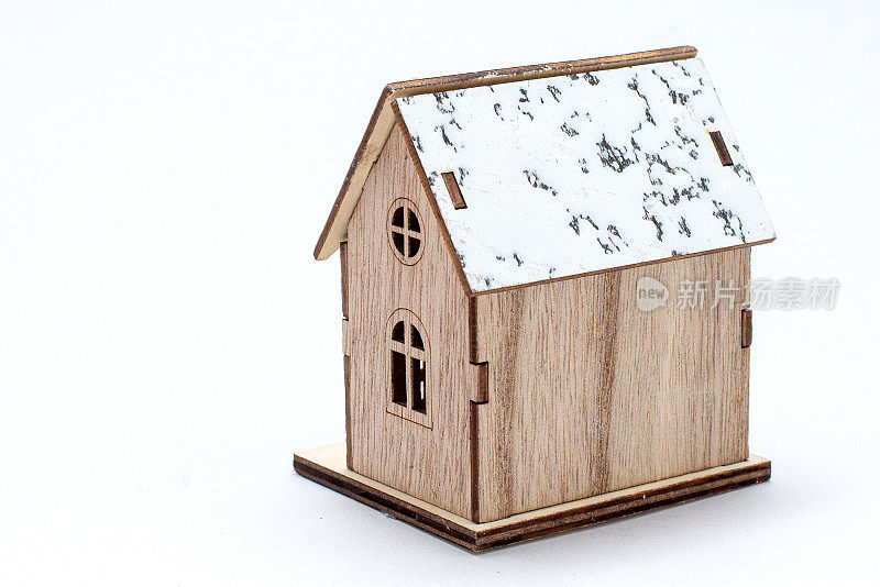 冬季风格的模型木屋，屋顶上有雪，木制栅栏，门窗。复古的木质家居装饰。玩具小属性模型孤立在白色背景上。概念房屋买卖