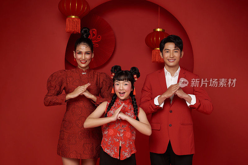 快乐的亚洲家庭穿着红色休闲服装，用传统的红色背景装饰，祝贺2024年中国新年快乐。