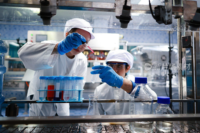 两名卫生学家检查了正在实验室生产的饮用水。