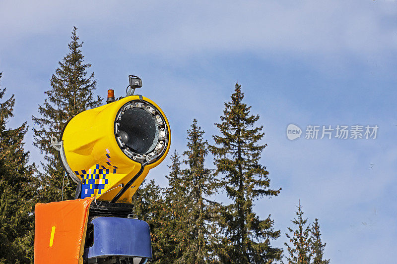 在一个阳光明媚的日子里，滑雪场斜坡上的造雪机。积极的娱乐活动