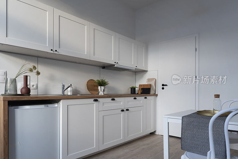 厨房作为家庭展示室内，配有舒适设计的木制厨房台面和厨房用具。用水龙头洗水槽。