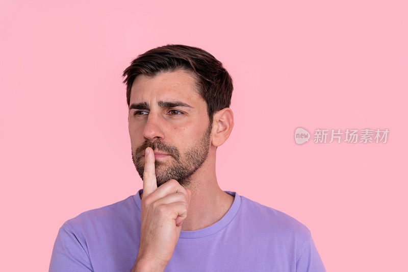 体贴的男人，手指放在嘴唇上，粉红色的背景