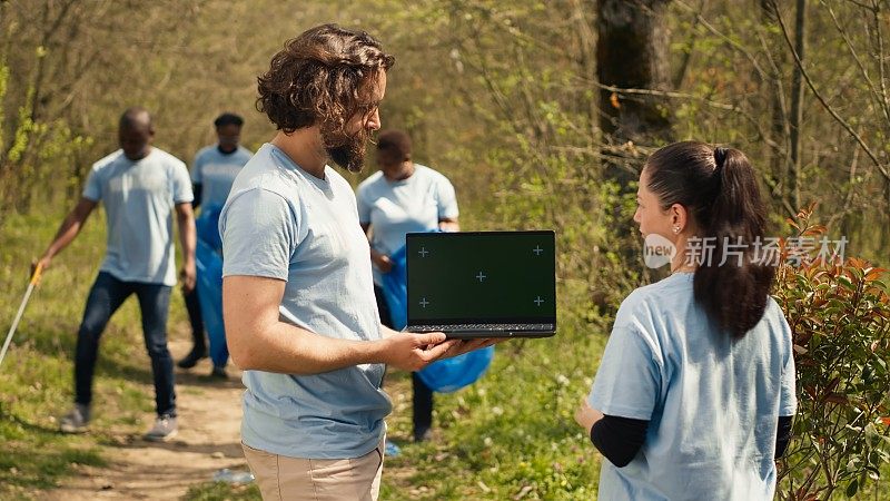 一组气候和自然活动家在森林附近使用带有绿屏的笔记本电脑